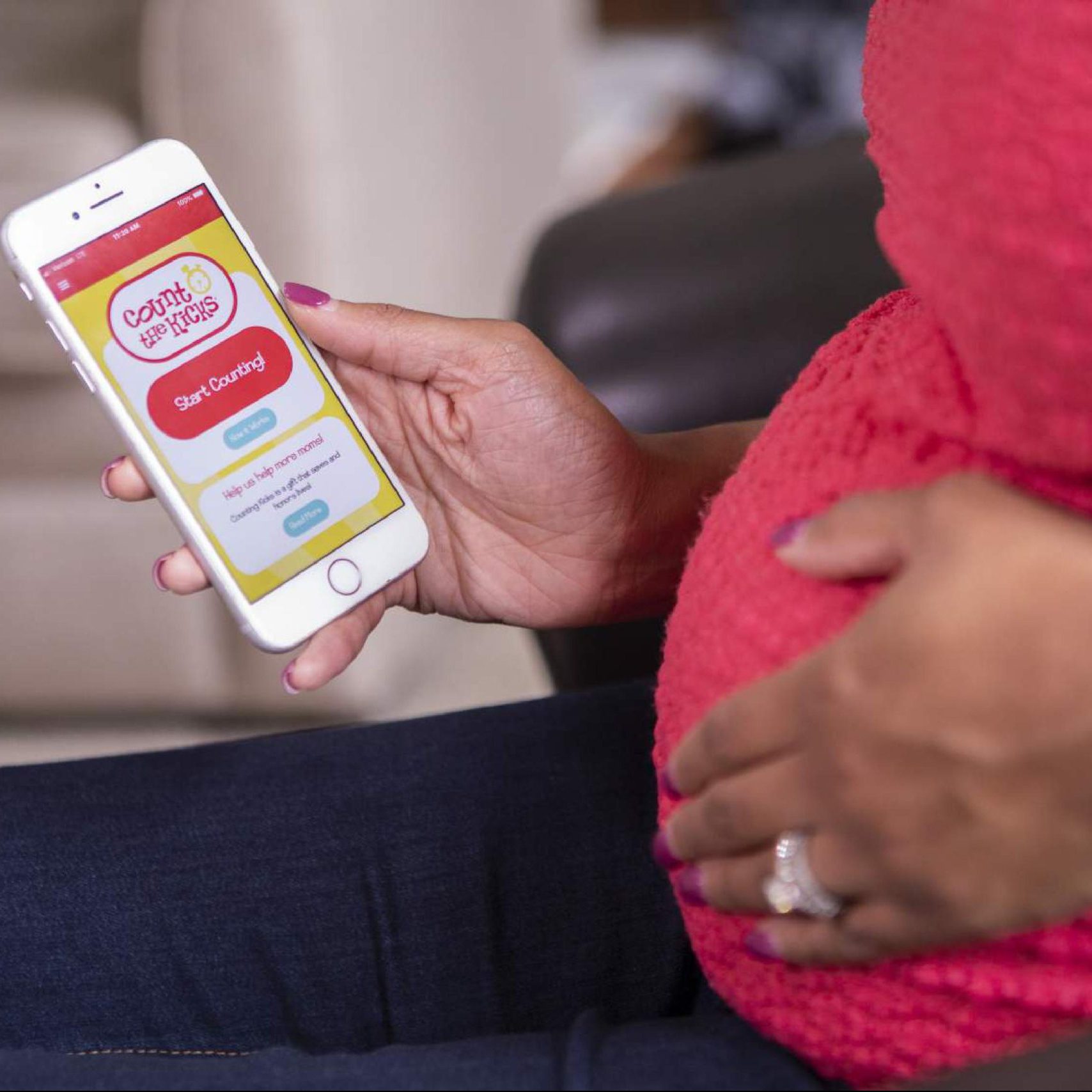 A pregnant mom uses the Count the Kicks app on her phone.