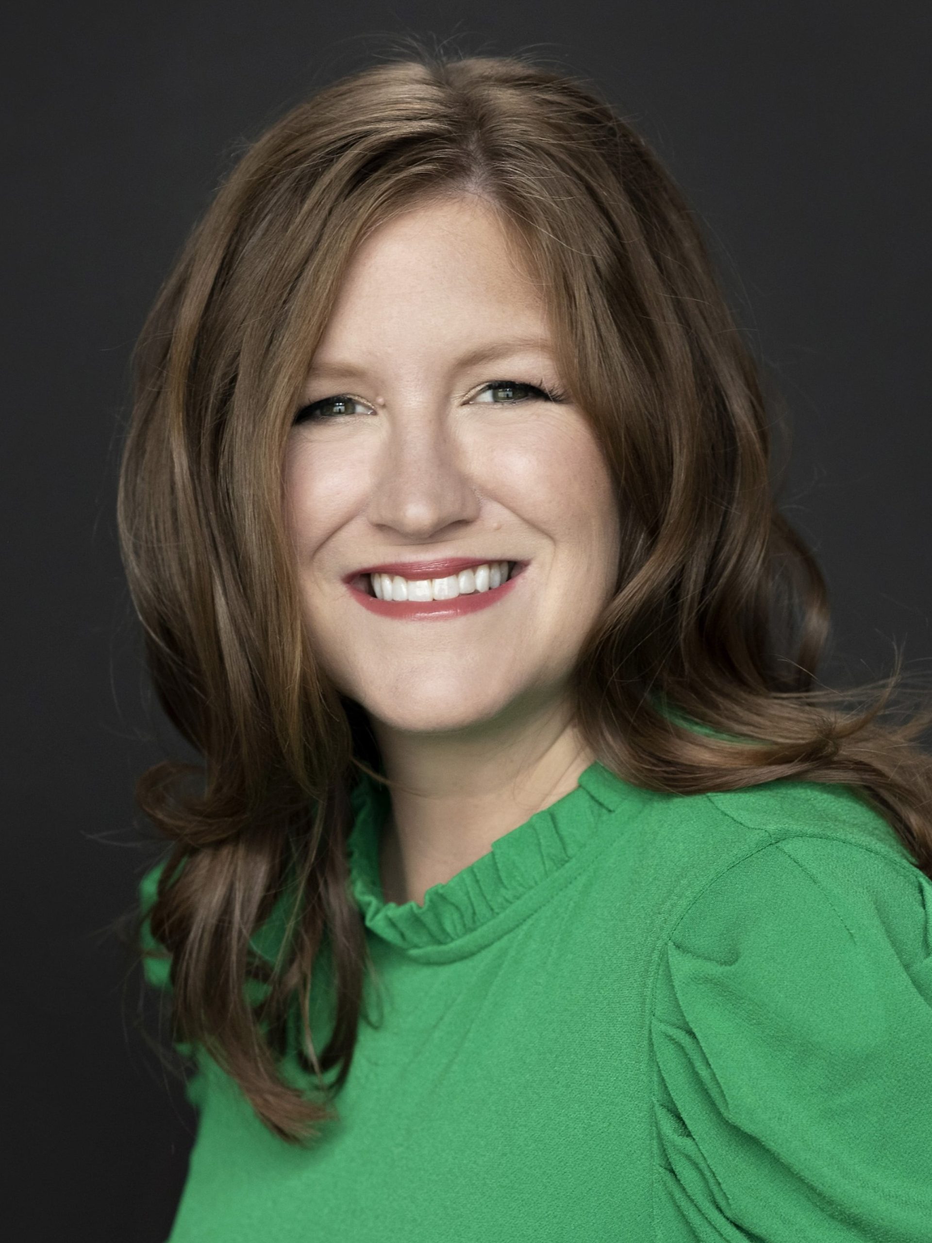A photo of Emily Price, CEO of Healthy Birth Day, Inc., wearing a green shirt.